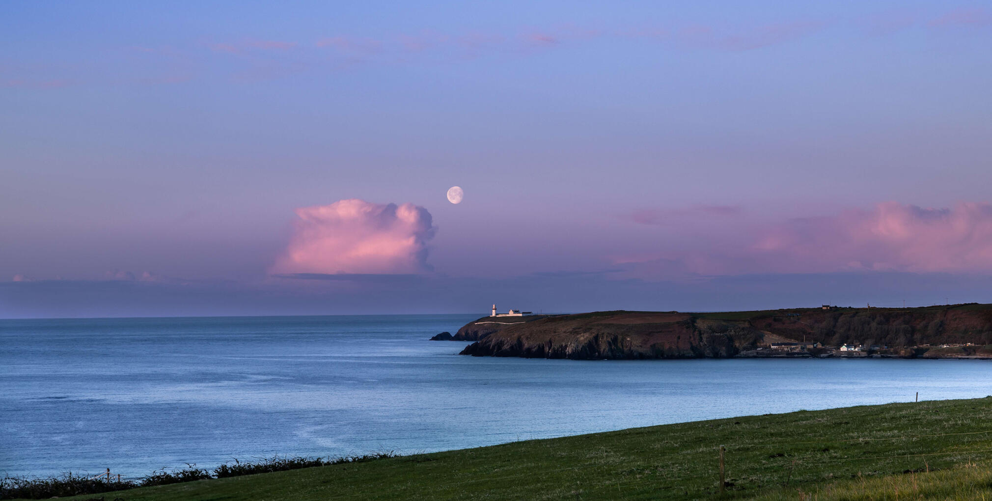 Galley Head Lighthouse at sunrise with the moon above the Atlantic coast in West Cork, Ireland.